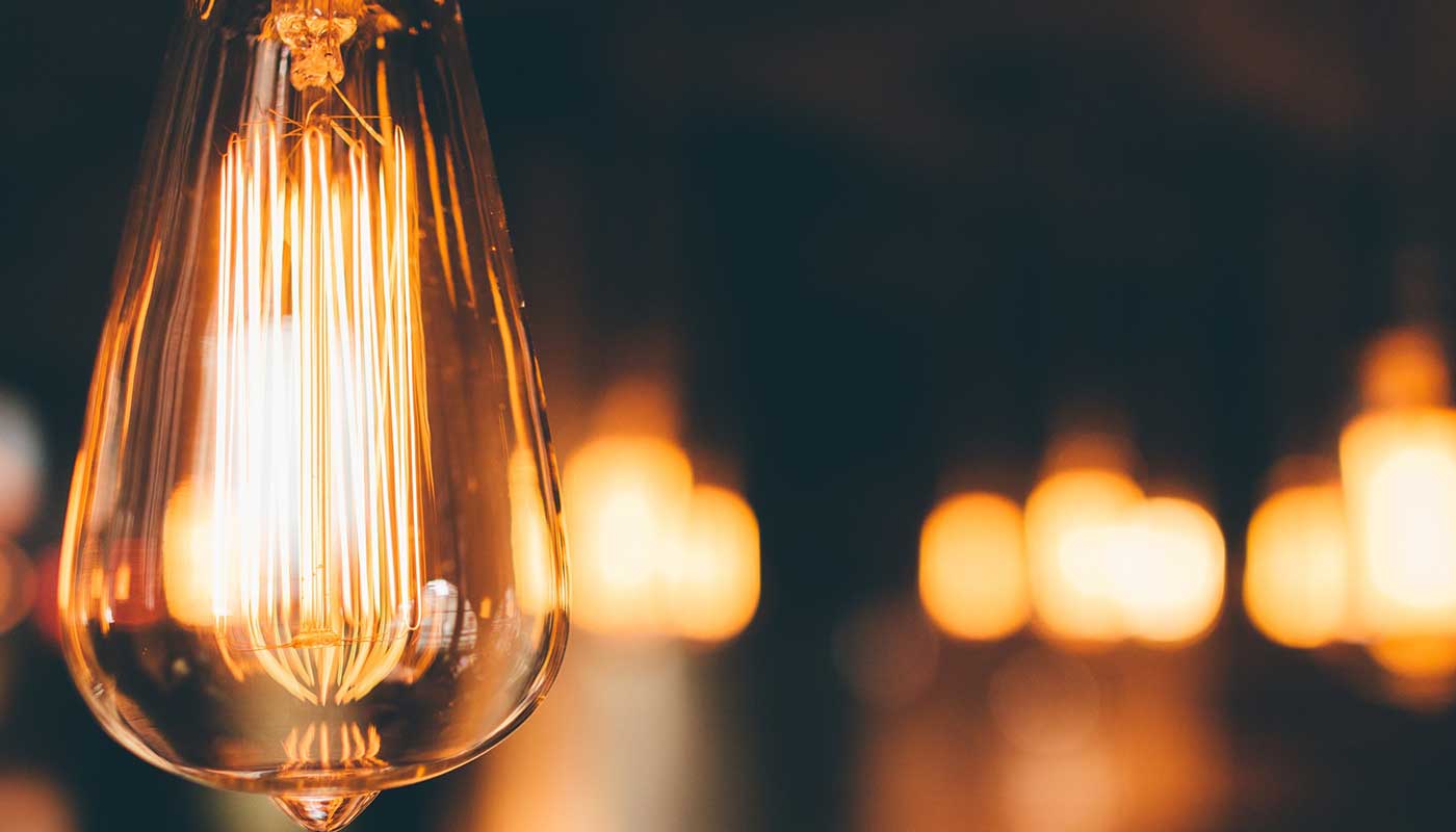 Hamilton electrician Apollo Electric: glowing Edison-style light bulb against a dark background